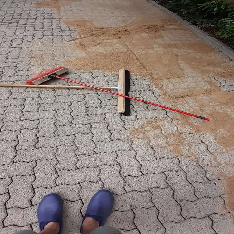 Ehrliches Handwerk in Hannover: Der Steinbotschafter beim manuellen Einkehren von Fugensand nach der Reinigung