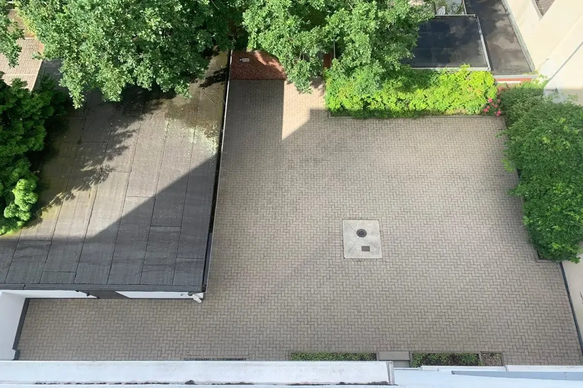 Steinreinigung Hannover durch Steinbotschafter: Das Bild zeigt die vollständige Beseitigung von Algen und Schmutz auf einem Garagenhof nach der Fachreinigung.